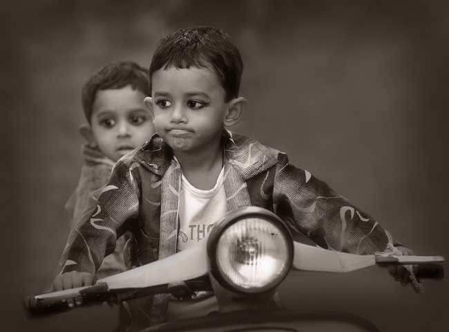 Two little boys sitting on a motor scooter