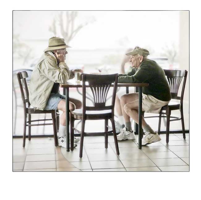 Two Senior Citizens Conversing at a Table