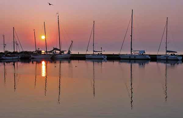 Sun rising over sailboats