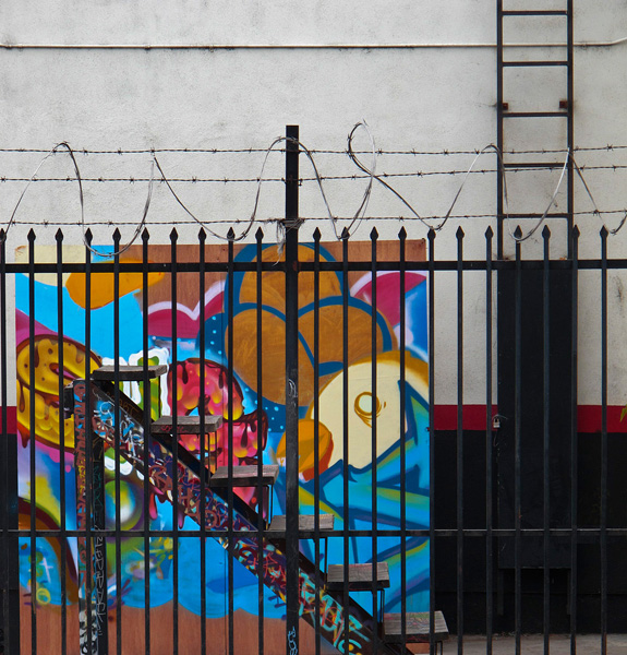 Colorful artwork in fenced parking area with black ladder in foreground