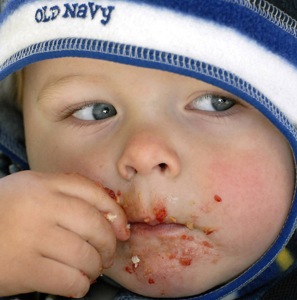 Small child in blue and white hat  with smeared mouth