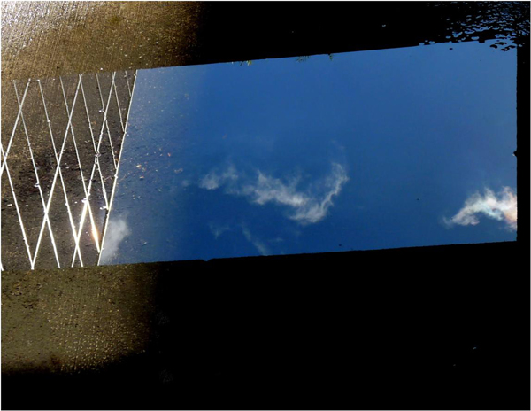 Blue sky and clouds reflected on glass placed on garage floor