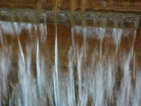 Macro shot of water flowing over the edge of a fountain