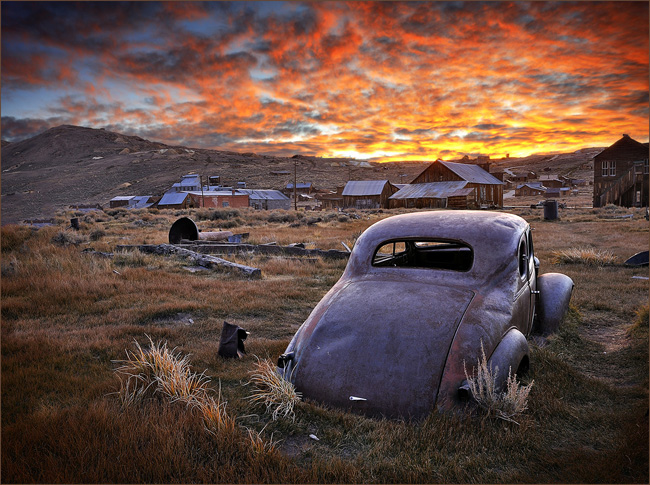 Old car in Bodie facing a blazing sunrise