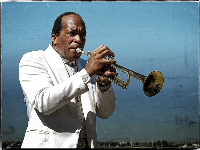 Black man in white suit playing the trumpet