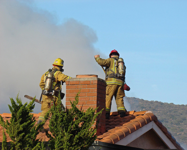 Two Firemen on Roof of Burning House