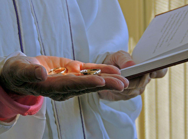 Minister's Hand Holding Two Golden Rings