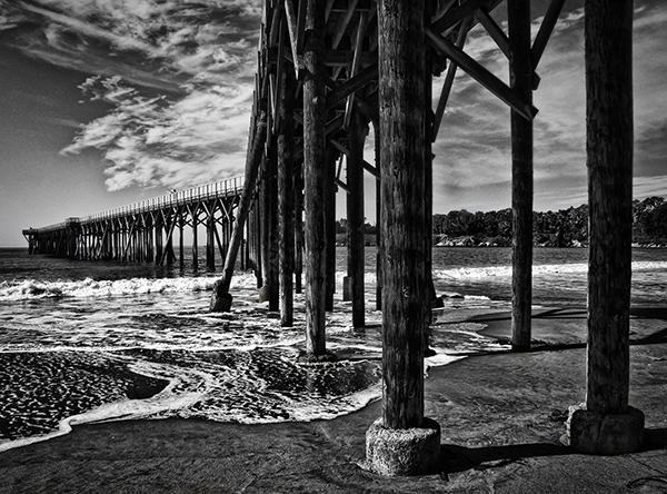 Pier pilings in foreground, with pier receding into the distance
