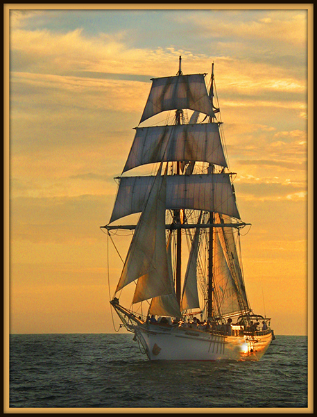 Tall Ship with Sails Illuminated by Glowing Sunset