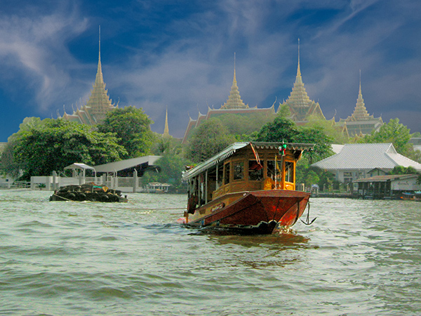 Gold and red boat in Thai harbor with temples in the background
