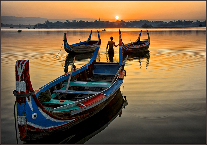Fisherman in boat facing the sunrise